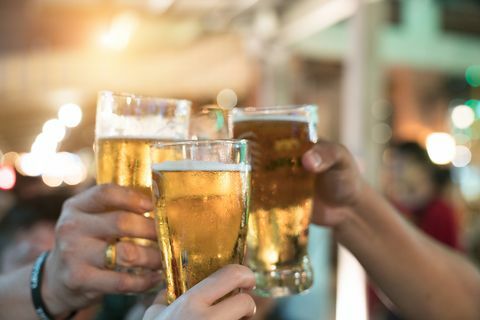 Venner skåler med glas let øl på pubben. Smuk baggrund af Oktoberfest. En gruppe unge mennesker mens de slapper af i baren. fint korn. Blødt fokus. Lavvandet DOF.