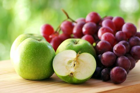 Æbler og druer på træbord