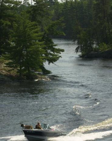 Kører gennem smalene, der fører til Kettle Falls, adskiller Rainy Lake og Lake Kabetogama på Grænsen mellem Minnesota og Ontario, en båd nærmer sig kajen ejet af National Park Service i Kettle Falls Hotel.