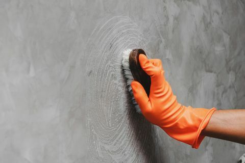 Beskåret hånd af mand rengøring grå væg