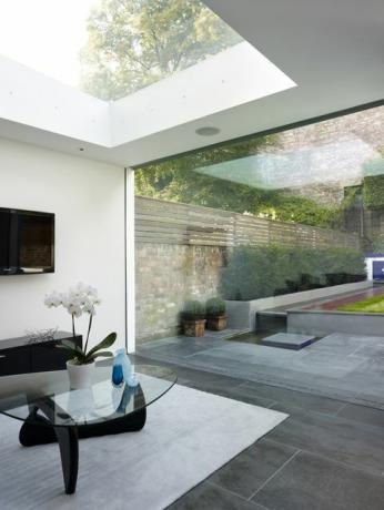 Moderne opholdsstue med ovenlysvindue og åben væg med udsigt til haven i Walham Grove, UK