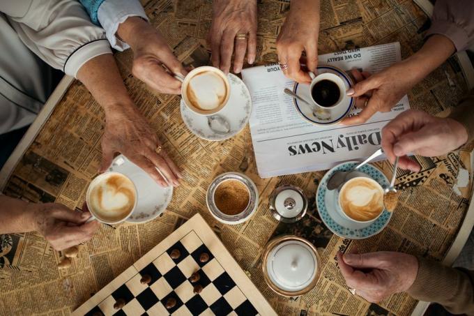 seniorvenner nyder tid sammen indendørs i cafe direkte over udsigten