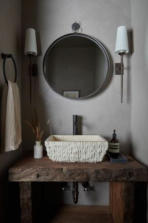 en badeværelsesvask med et rundt spejl