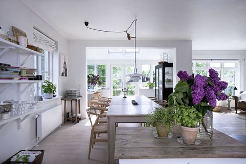 Lys, venlig og hyggelig stue i skandinavisk stil. Et luftigt køkken med hvide vægge og enhedsdøre; En ø med blomster.