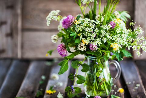 Buket med vilde blomster i glaskrukke på træbord, sommerkoncept