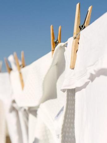 hvidt tøj hængt ud for at tørre på en vaskelinje i den lyse varme sol baggrund er en klar blå himmel