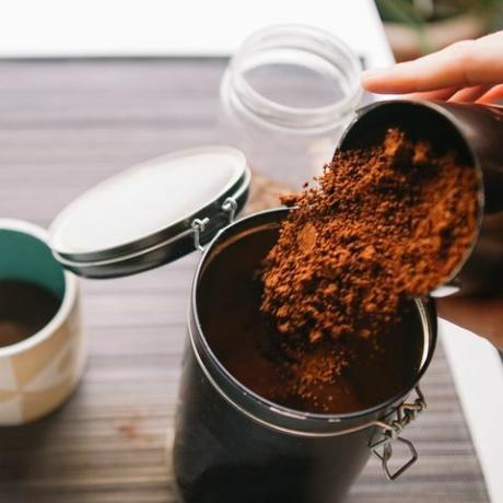 kaffegrums haven beskårne hænder hælde malet kaffe i genanvendelig beholder