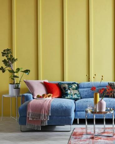 lys stue med gul panelvæg og blå sofa