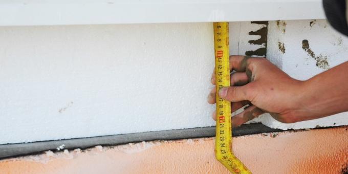 husfundament isolering med styrofoam varmeisoleringsplade entreprenør hånd med målebånd