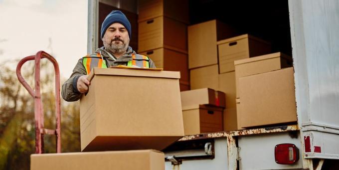 mandlig arbejder læsser papkasser af fra varevogn
