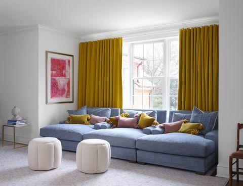 blå sofa, gule gardiner, lyserøde og gule hynder