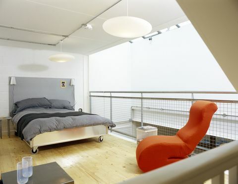 Moderne soveværelse med gråt dynebetræk og lys orange stol