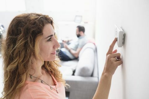 Kvinde justerer termostaten derhjemme