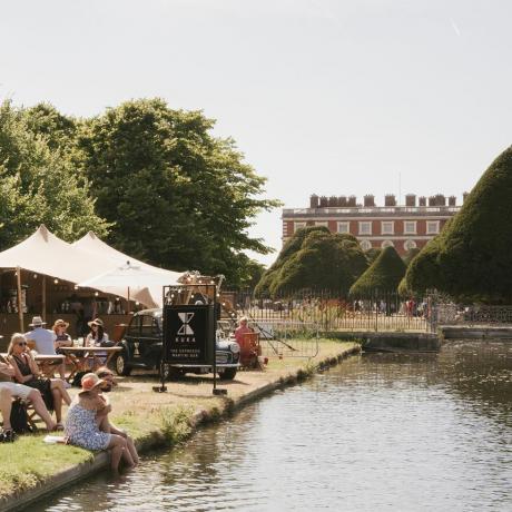 besøgende slapper af i kuka bar ved det lange vand på rhs hampton court palace garden festival 2022