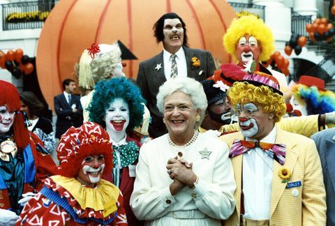 dette fotografi er af førstedame, barbara bush, der griner, mens hun poserer sammen med udklædte kunstnere, en gruppe af klovne og en enlig varulv på den sydlige grund af det hvide hus som en del af en halloween fest