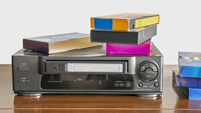 gammel videokassetteafspiller med gamle videobånd på et træskab